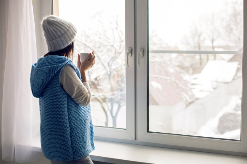 Female homeowner enjoying her new air scrubber for better indoor air quality, while looking out window.